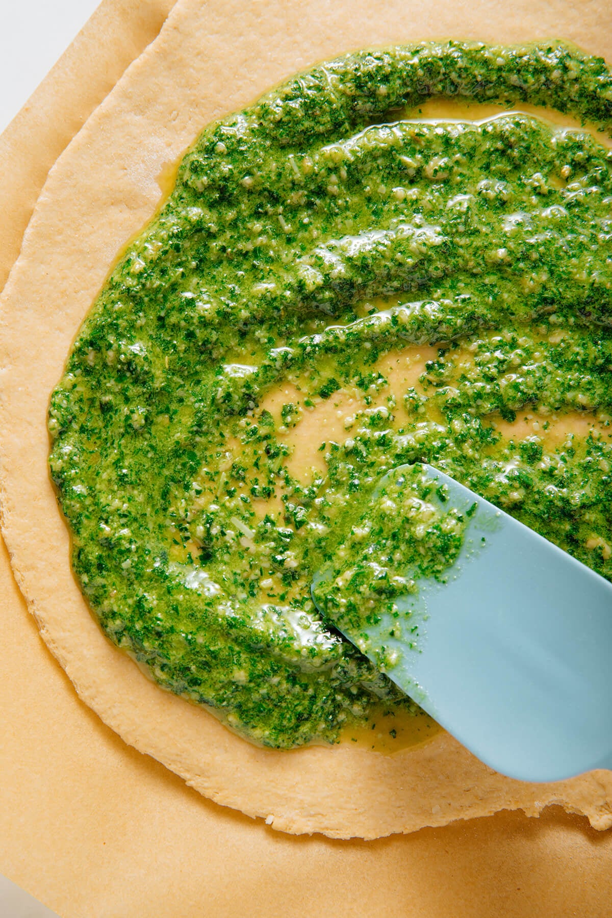 spreading pesto on pizza